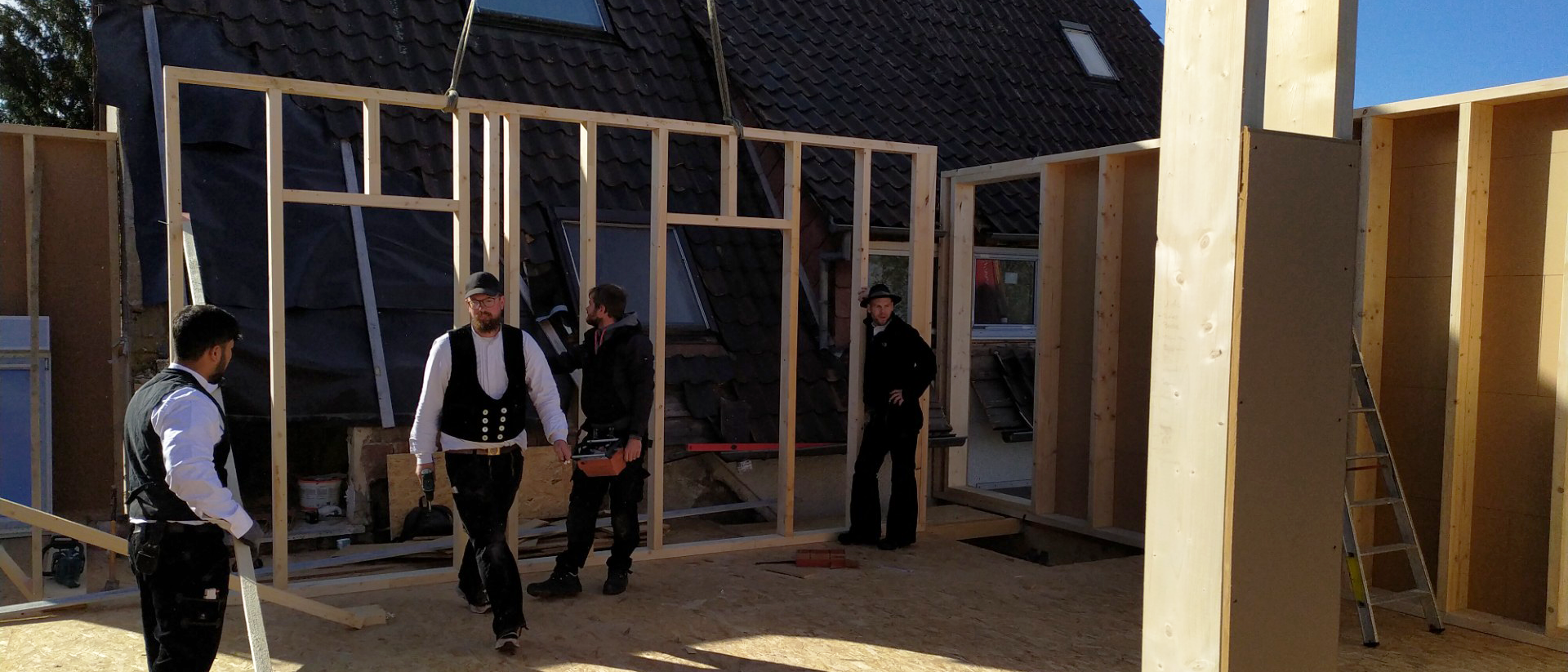 Neubau in der Umsetzung: Zimmerleute arbeiten im Holzrahmenbau an der Innenstruktur eines Hauses und koordinieren präzise die nächsten Bauabschnitte.